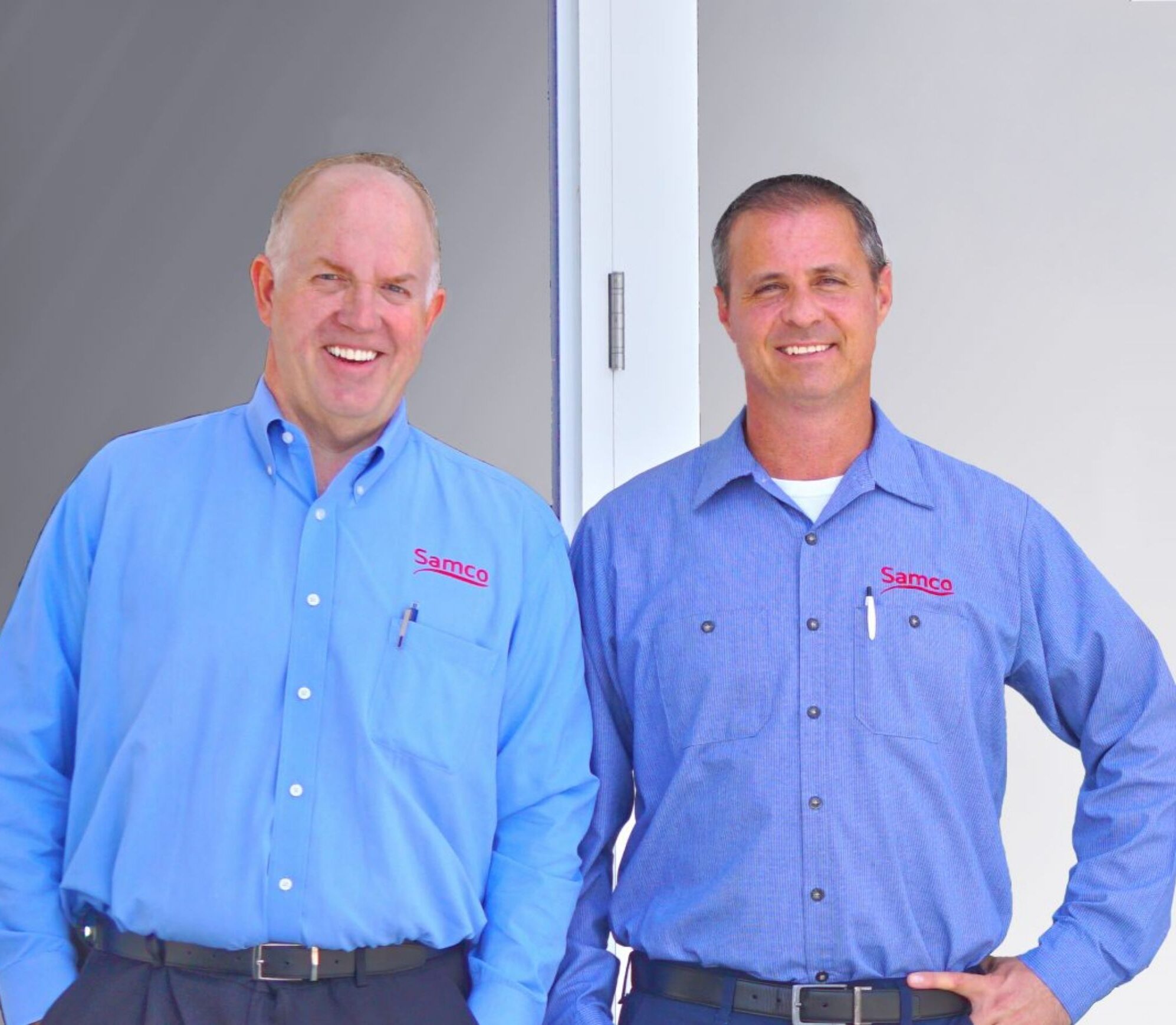 Two men in Samco shirts stand side by side smiling.