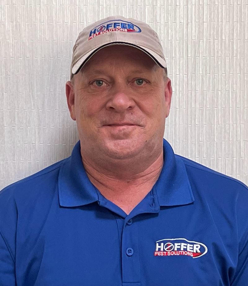 Man in Hoffer Pest Solutions shirt and cap smiling.