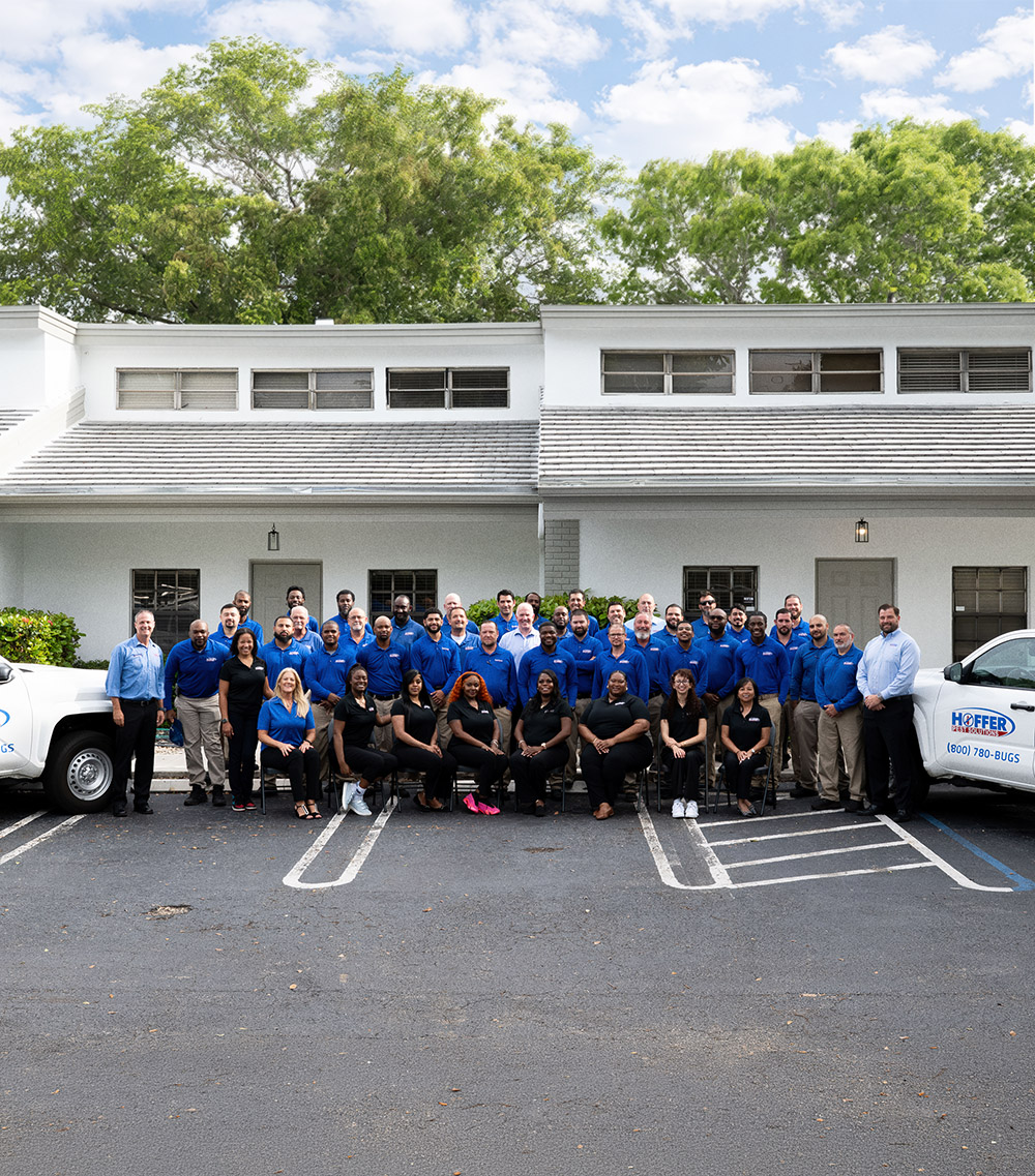 Group poses together in front of white building.