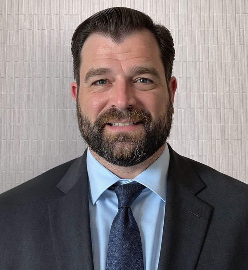 Man with dark hair and beard smiles.
