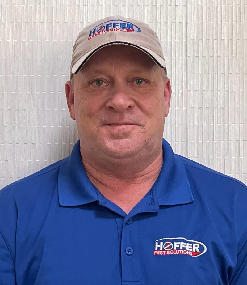 Man in Hoffer Pest Solutions shirt and cap smiling.