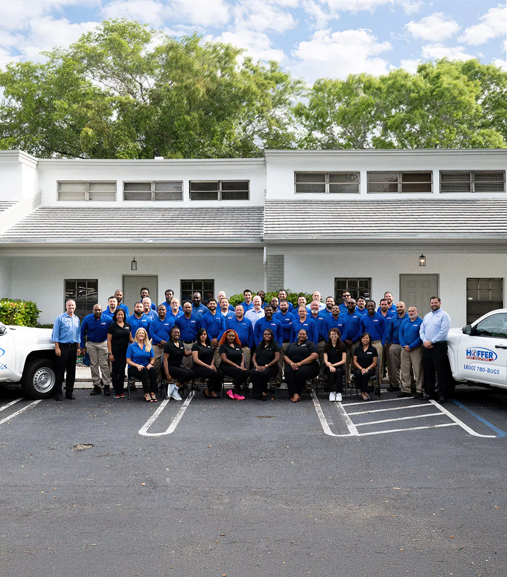 Group poses together in front of white building.