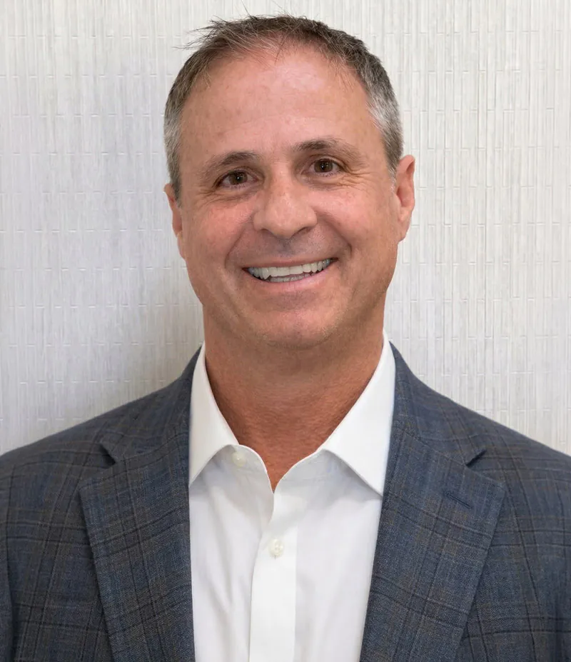 Smiling man wears a blue plaid suit jacket.